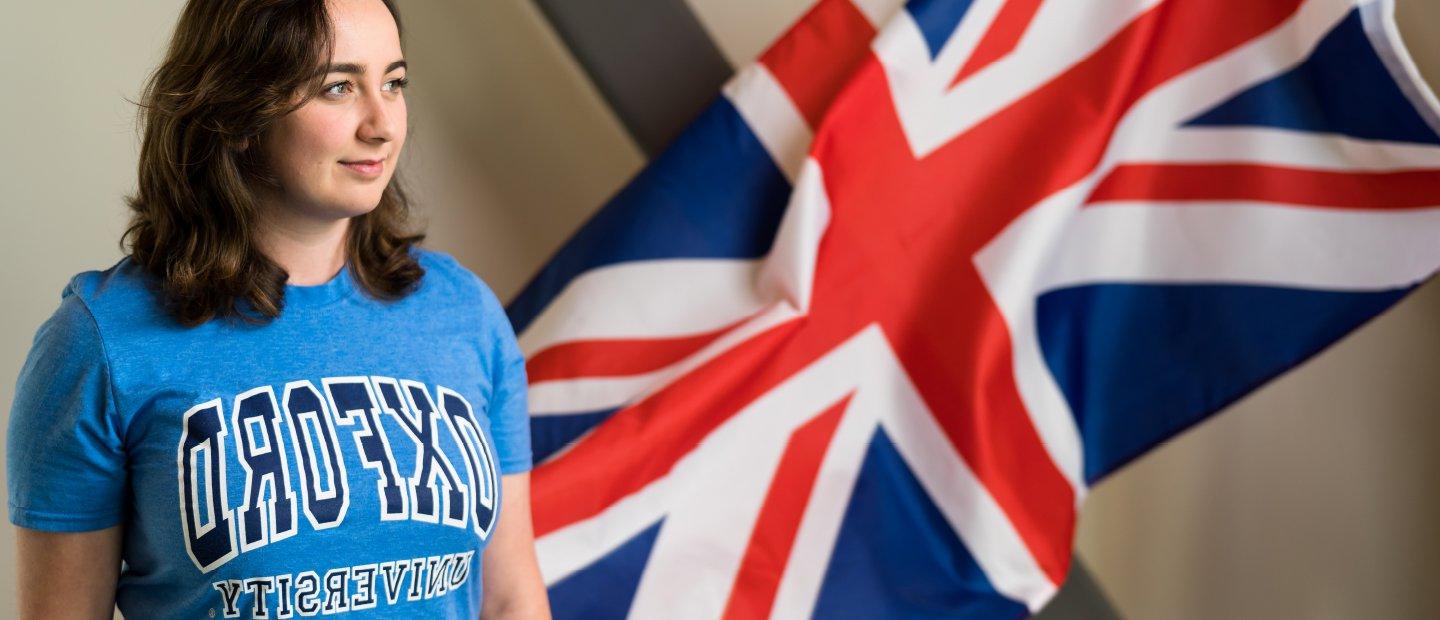 A girl wearing an 牛津大学 shirt, posing in front of a British flag.